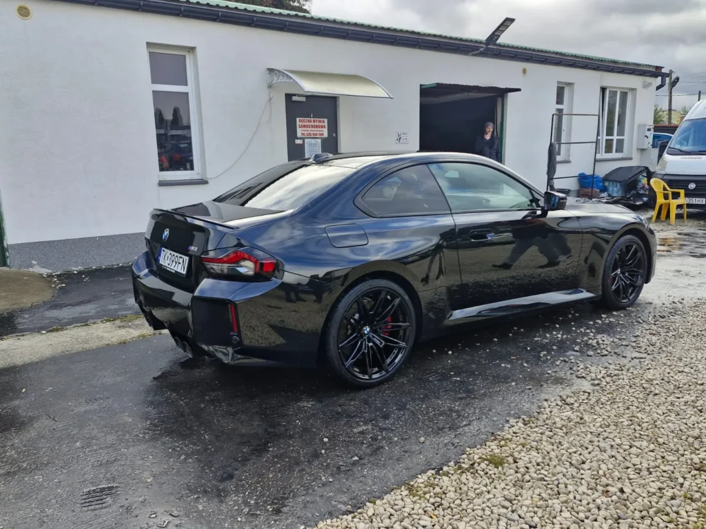 BMW M2 2024 czarne – ujęcie tylne z boku, samochód sportowy premium do wynajmu w APKARS