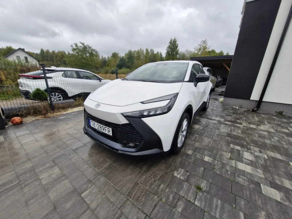 "Nowa Toyota C-HR 2025 biała – widok 3/4 z przodu, kompaktowy hybrydowy SUV coupe dostępny w wynajmie długoterminowym APKARS