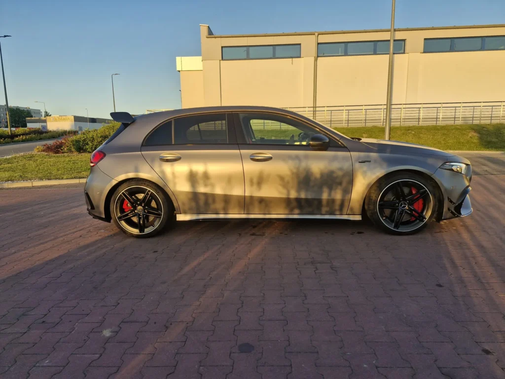 Mercedes A45s AMG 2022 – widok boczny, matowy szary sportowy hot-hatch z czerwonymi zaciskami i czarnymi felgami